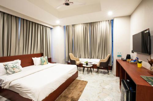 a hotel room with a bed and a desk and a tv at Aarchh Regency Noida in Noida