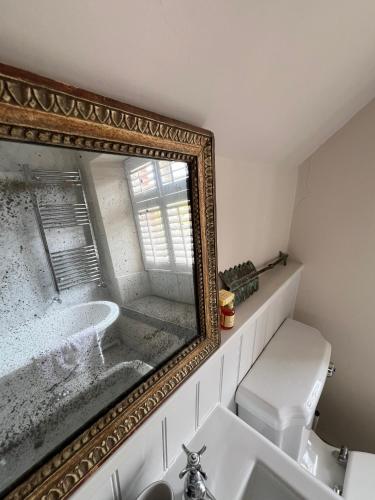 a bathroom with a mirror over a sink and a toilet at Uplands Guest House in Ledbury