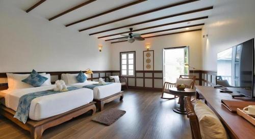 a large bedroom with two beds and a television at My BanLao Hotel in Luang Prabang
