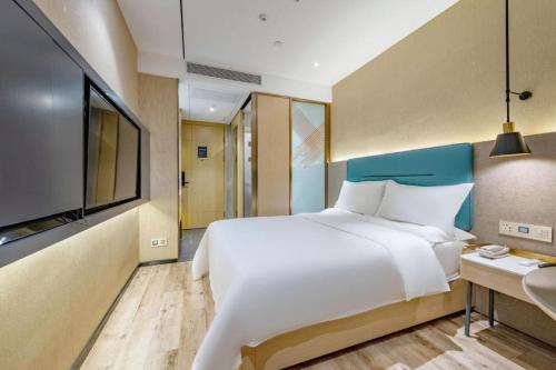 a bedroom with a large bed and a flat screen tv at ZMAX Hotels Shenzhen Lianhuacun Metro Station in Shenzhen