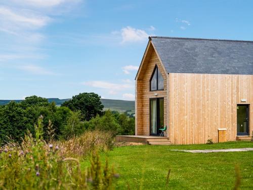 a wooden house on a grassy field with trees at Bothy 5 - Uk50475 in Greenhaugh