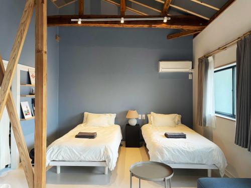 ein Zimmer mit zwei Betten und einem Tisch und Stühlen in der Unterkunft Coranne in Sasebo