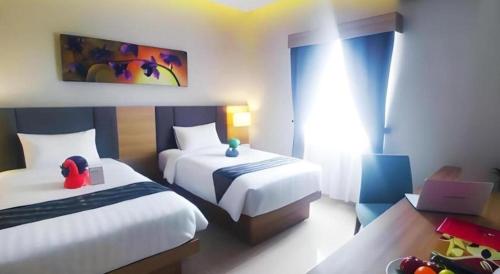 a bedroom with two beds and a desk with a laptop at Orchardz Hotel Gajah Mada in Pontianak