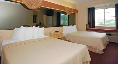 a hotel room with two white beds and a window at Quality Inn & Suites in Mount Juliet