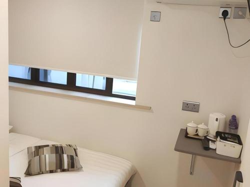 a white room with a bed and a window at Goodrich Hotel in Hong Kong