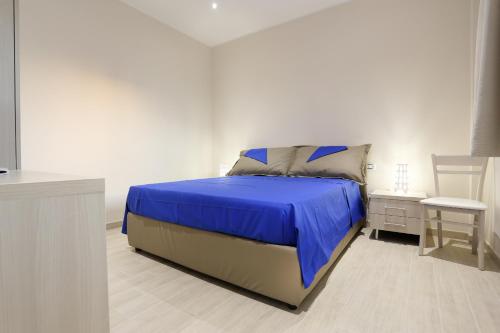 sypialnia z łóżkiem z niebieską pościelą i krzesłem w obiekcie Marea Sicula Home w Syrakuzach