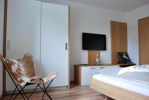 ein Schlafzimmer mit einem Bett, einem Stuhl und einem TV in der Unterkunft Haus Pflaum in Dellach im Drautal