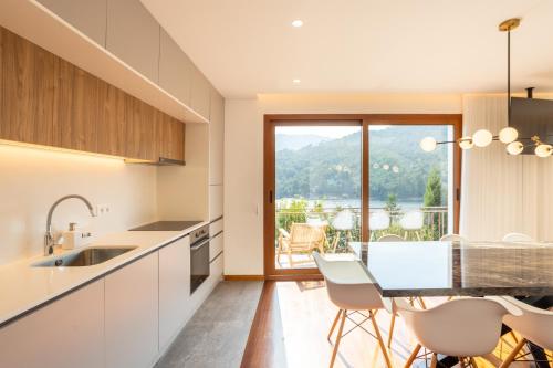 a kitchen with a table and chairs and a balcony at Casas do Picoto - Gerês Nature and Natural River Beach in Terras de Bouro