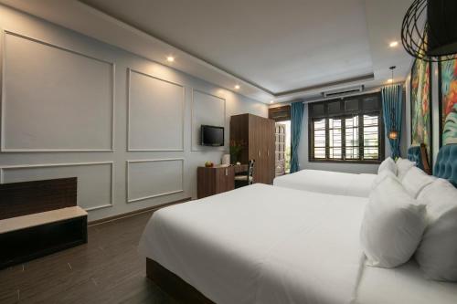 a bedroom with a large white bed and a television at Elegance Premium Hotel in Hanoi