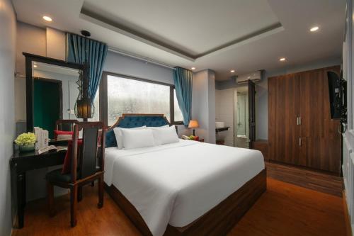 a bedroom with a large white bed and a desk at Elegance Premium Hotel in Hanoi
