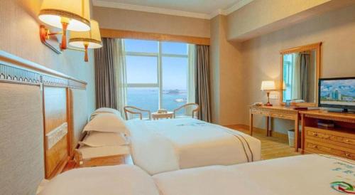 a hotel room with two beds and a television at Zhuhai Dehan Hotel in Zhuhai