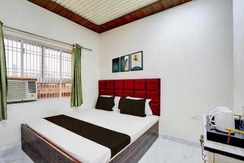 a bedroom with a bed with a red headboard and a window at Super Hotel O Mathura Central Railway Junction Formerly Bhagwati Palace in Mathura