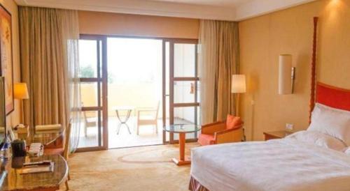 a hotel room with a bed and a sliding glass door at Ocean Spring Metropark Hotel Zhuhai in Zhuhai