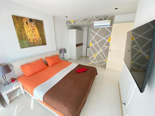 a bedroom with a large bed with orange pillows at The Gallery Condominium M in Jomtien Beach