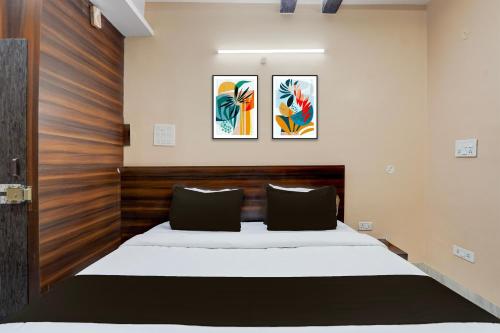 a bedroom with a bed and two paintings on the wall at Super Collection O Patliputra Sports Complex Formerly Wellfood Inn in Patna