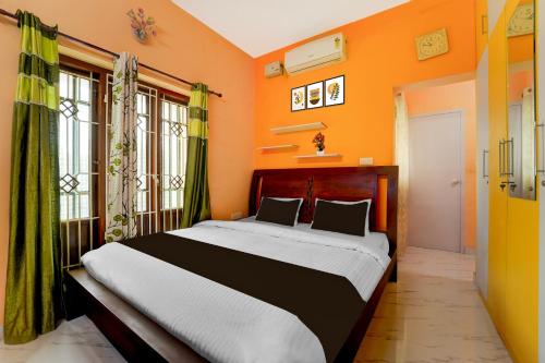 a bedroom with a bed with orange walls and windows at Hotel O NIMS Hospital Formerly White Castle in Bālarāmpuram