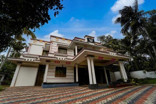 a building in front of a palm tree at Hotel O NIMS Hospital Formerly White Castle in Bālarāmpuram
