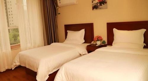two beds sitting next to each other in a bedroom at GreenTree Inn Luoyang Zhongzheng Street Express Hotel in Luoyang