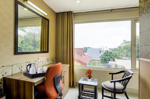a room with a desk and chairs and a large window at Super Townhouse Oak ONGC Crossway Formerly Hotel Gold Stone Comfort in Dehradun