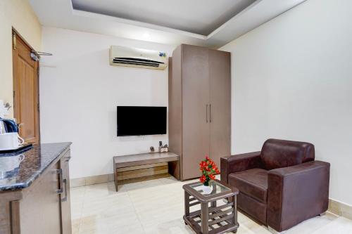 a living room with a chair and a television at Super Townhouse Oak ONGC Crossway Formerly Hotel Gold Stone Comfort in Dehradun