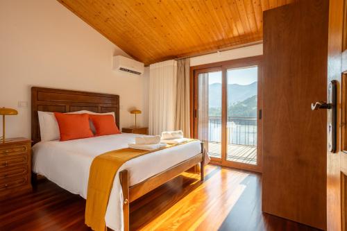 a bedroom with a bed and a large window at Casas do Picoto - Gerês Nature and Natural River Beach in Geres