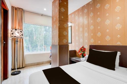 a bedroom with a large bed and a window at Super Townhouse Oak ONGC Crossway Formerly Hotel Gold Stone Comfort in Dehradun