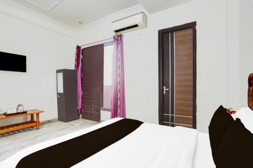 a bedroom with a bed and a large window at Townhouse Johri Enclave Metro Station Formerly Second Home in New Delhi