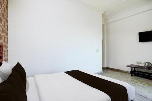 a white bed in a white room with a television at Townhouse Johri Enclave Metro Station Formerly Second Home in New Delhi