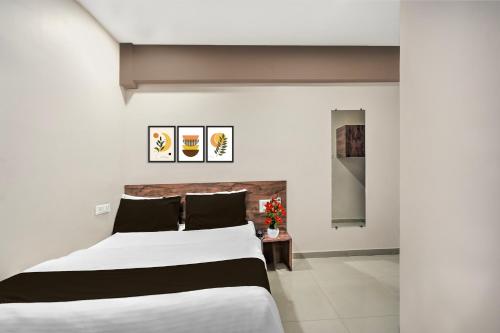 a bedroom with a large white bed with black pillows at Super Collection O Palampur Surat Formerly Hotel Royal Paradise in Bhatha