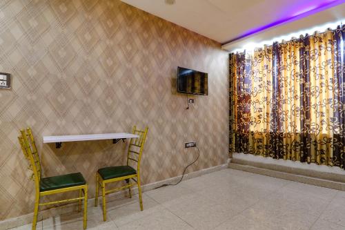 a room with two chairs and a table and a television at FabHotel Gold Galaxy in Kānpur