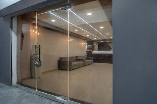 a glass door in a room with a couch at Super Collection O Palampur Surat Formerly Hotel Royal Paradise in Bhatha