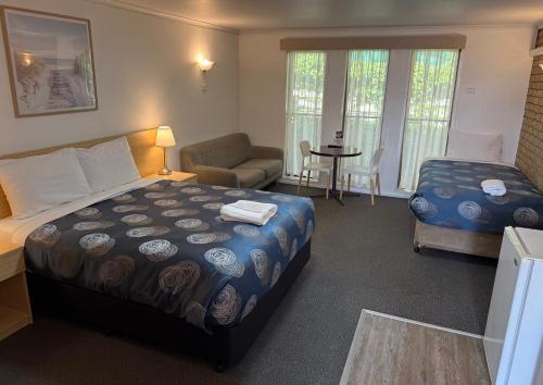 a bedroom with a bed and a chair and a desk at Tropicana Motor Inn in Cowes