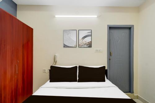 a bedroom with a bed with black and white sheets at Super Collection O Khajaguda Hills Formerly Sri Balaji Luxary Rooms in Gachibowli