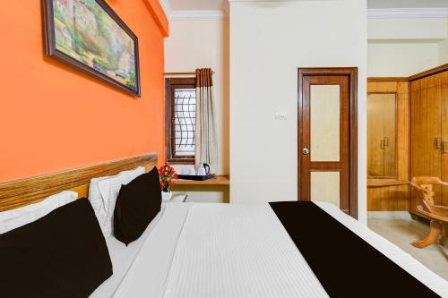 a bedroom with a bed with an orange wall at Super Collection O Sharath City Mall Formerly Delight Inn Gachibowli in Kondapur