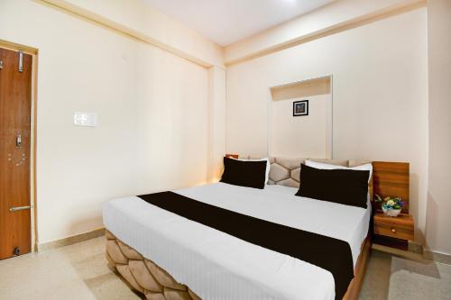 a bedroom with a large white bed with black pillows at Super Townhouse Kumhrar Archeological Park Formerly Hotel Karuna Palace in Gulzārbāgh