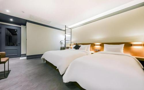 a hotel room with two beds and a chair at Cheongju Maryjane Hotel in Cheongju
