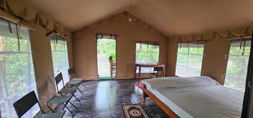 a bedroom in a tent with a bed and chairs at Athulyam Kanha, kanha national park, mukki gate in Khāpa
