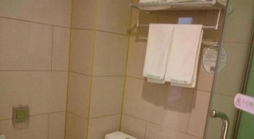 a bathroom with a toilet and towels on a wall at GreenTree Inn Qingdao Jiaozhou Jiaoping Road Express Hotel in Qingdao