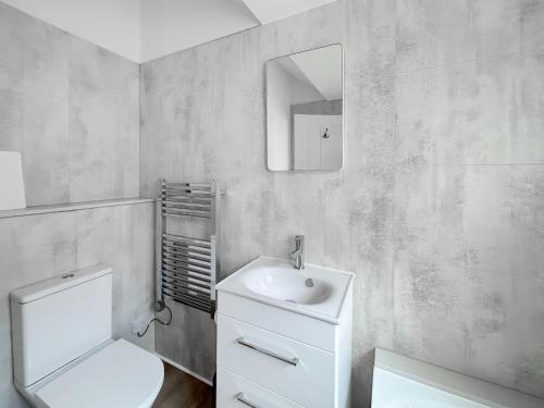 a bathroom with a toilet and a sink and a mirror at Seabreeze Retreat - Uk49968 in Worthing