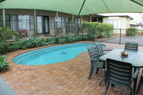 a swimming pool with a table and chairs and an umbrella at Lake Forbes Motel in Forbes