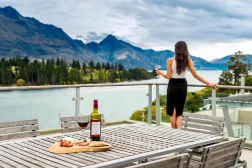 a woman standing on a table with a glass of wine at Oaks Queenstown Club Suites in Queenstown