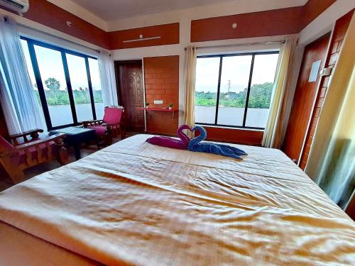 a large bed in a room with large windows at Abaca AuroVibe in Kuilapayam
