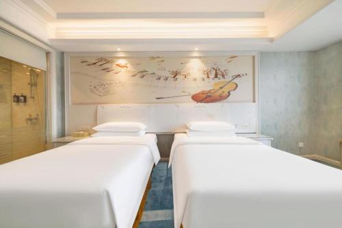 a row of white beds in a room at Vienna Hotel Guiyang Jiaxiulou Jichang Road in Guiyang