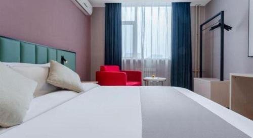 a bedroom with a large white bed and a red chair at Zhangye Pinmu Hotel(Yuncheng Zhongyin Avenue Store) in Yuncheng