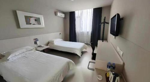 a hotel room with two beds and a flat screen tv at Zhangye Pinmu Hotel(Yuncheng Zhongyin Avenue Store) in Yuncheng