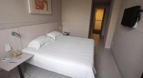 a bedroom with a bed and a table with a phone at Zhangye Pinmu Hotel(Yuncheng Zhongyin Avenue Store) in Yuncheng