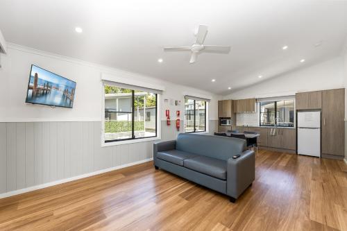 a living room with a couch and a kitchen at Heatherbrae Holiday Village in Heatherbrae