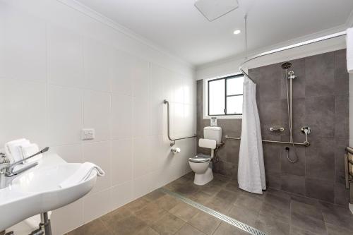 a bathroom with a shower and a toilet and a sink at Pacific Gardens Village in Heatherbrae
