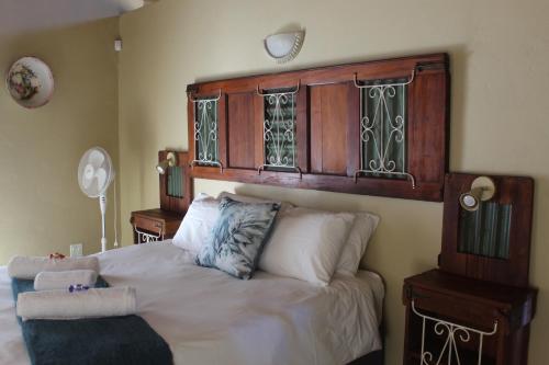 a bedroom with a bed with a wooden headboard at Shamba Yetu Mountain Lodge in Maanhaarrand