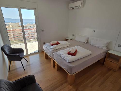 two beds in a room with a large window at 5 Sterne HERA City Apartment mit Meerblick in Lávrion